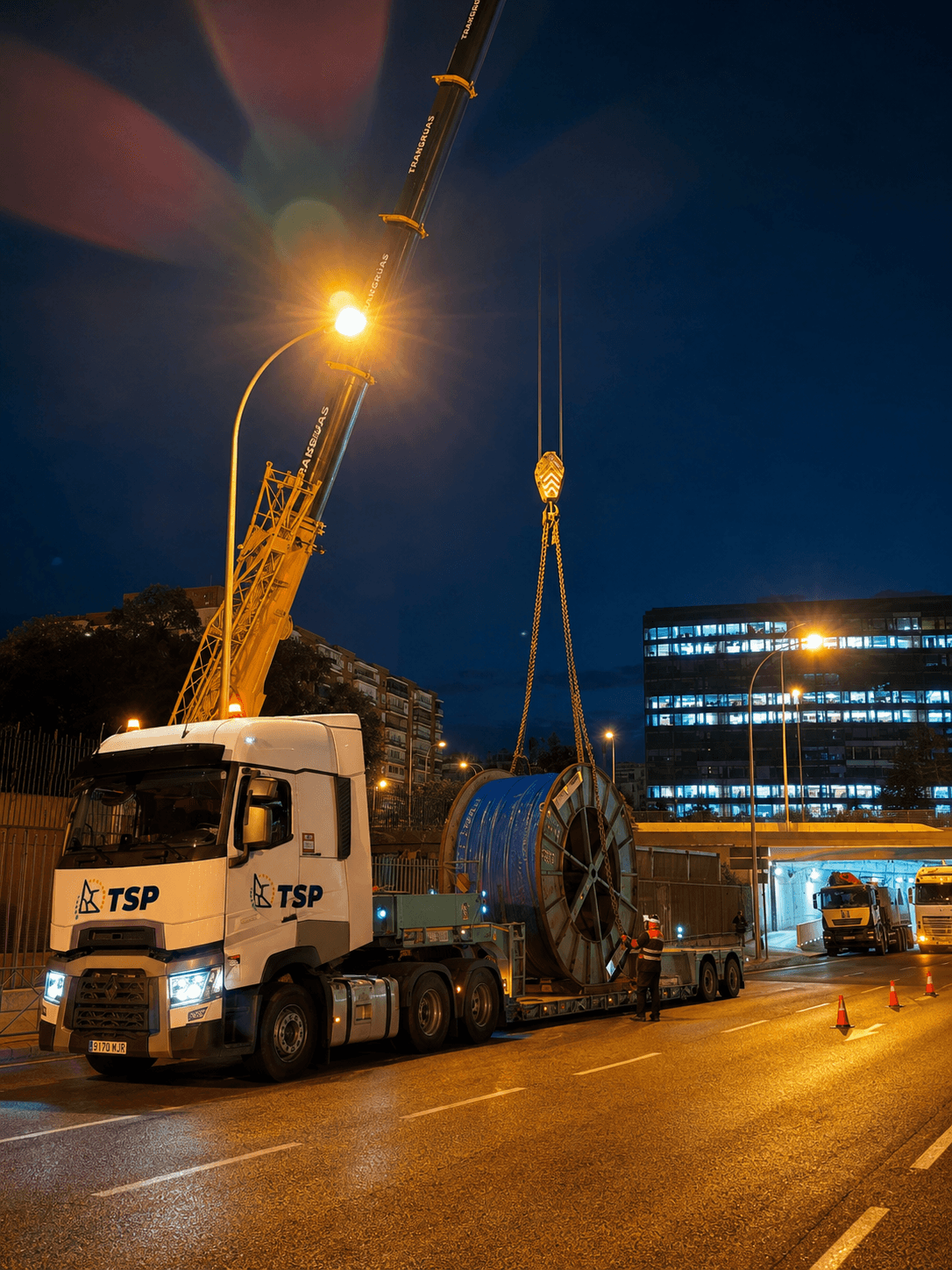 Camión de TSP durante la descarga nocturna de una gran bobina mediante una grúa